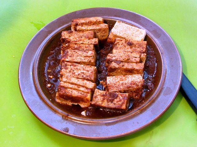 Plate of frozen and thawed tofu, soaking up sauce.