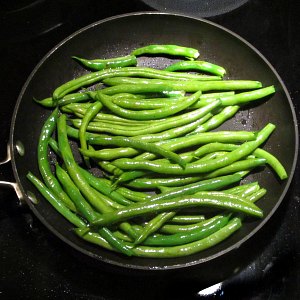 Saute fresh green beans in a pan.