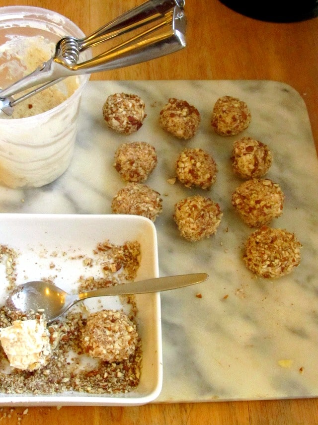 Rolling Onion Cheese Bites in chopped nuts.